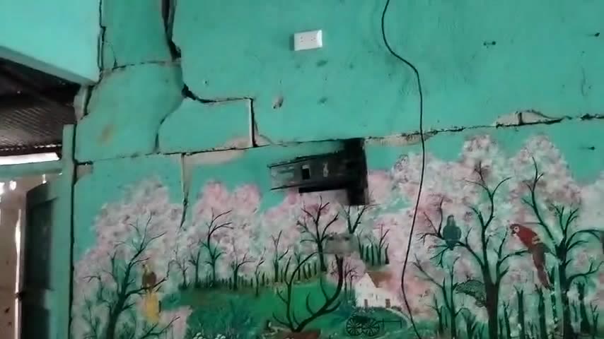 Pared pintada con un mural de árboles, partida por grietas