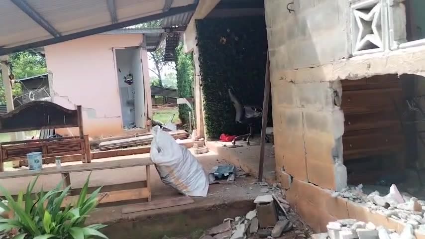 Corredor de la casa con escombros y una pared abierta